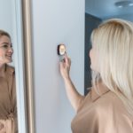 Close Up Of Woman Adjusting Central Heating Temperature At Home On Thermostat.