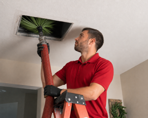 Professional duct cleaning process showing technician removing debris from ceiling vent